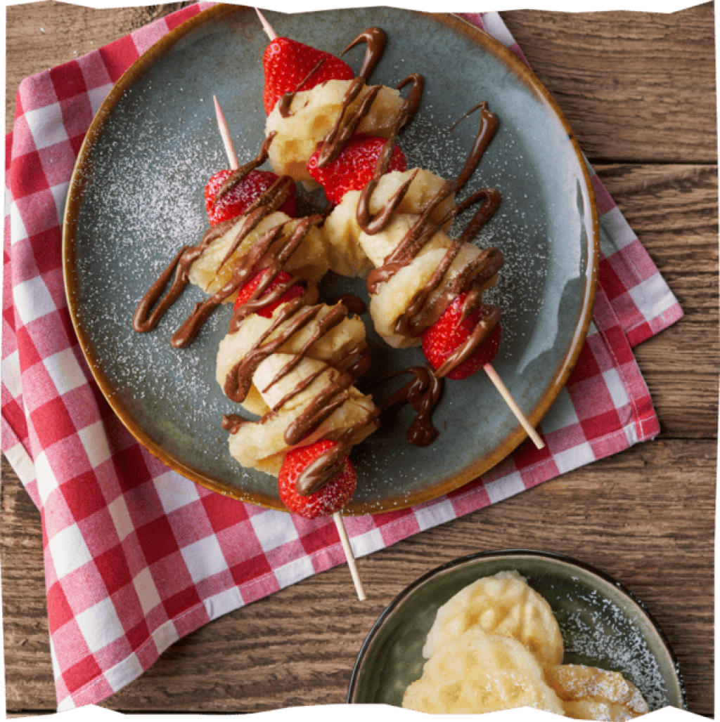 Fruchtig-Süße Waffelspieße mit Bananen, Kartoffelklößen, Erdbeeren und Schokosoße.