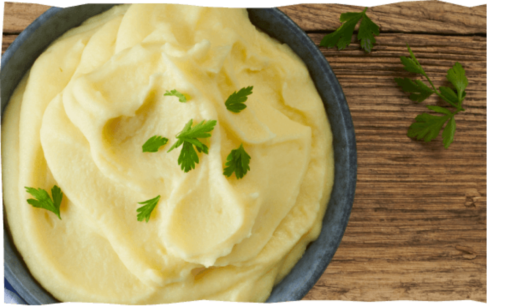 Cremiges Kartoffelpüree mit Kräutern auf Holztisch.