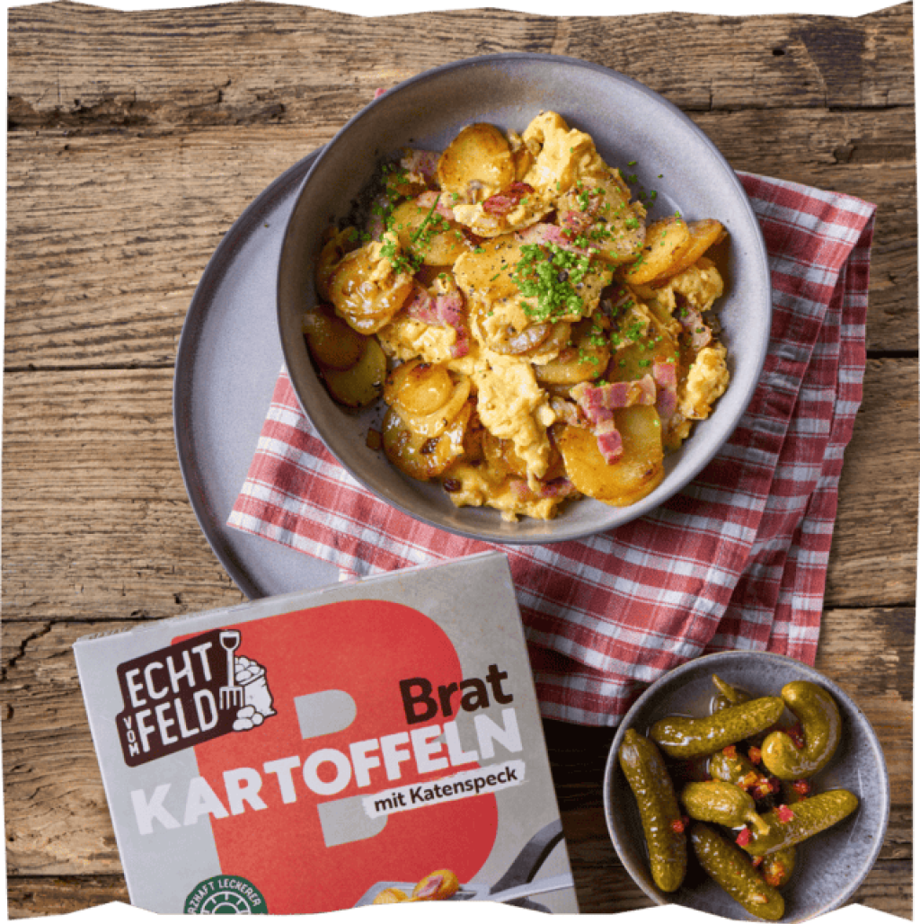Bauernfrühstück serviert mit Gurken und der Echt vom Feld Verpackung für Bratkartoffeln mit Speck zur Visualisierung.