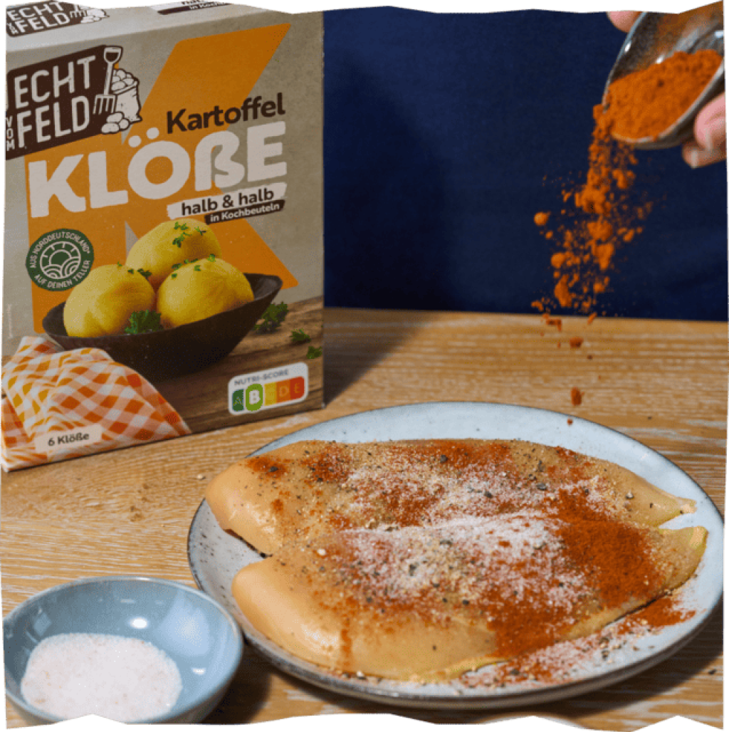 Mit Paprika, Knoblauch, Salz und Pfeffer gewürztes Hähnchenbrustfilet vor einer Echt vom Feld Kartoffelklße-Packung.