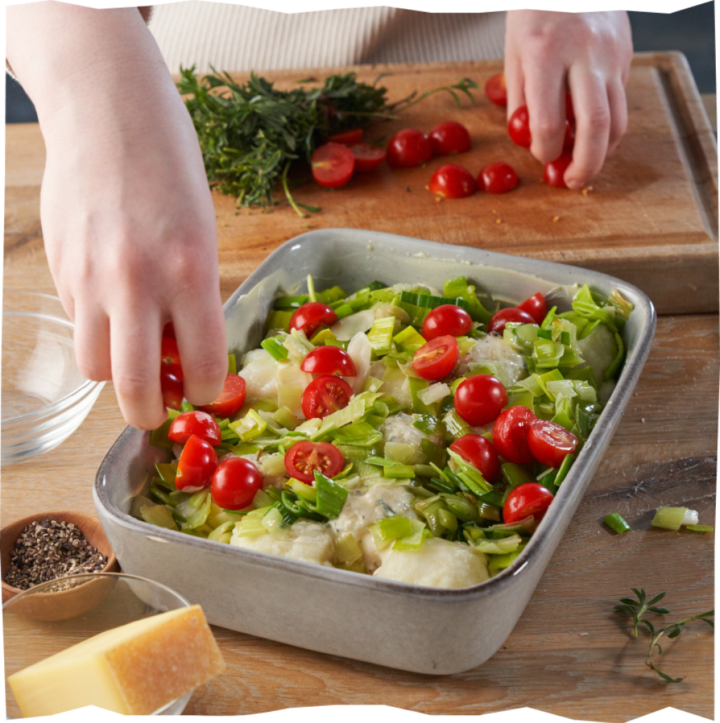 Kirschtomaten halbieren und mit dem Lauch in die Auflaufform füllen.