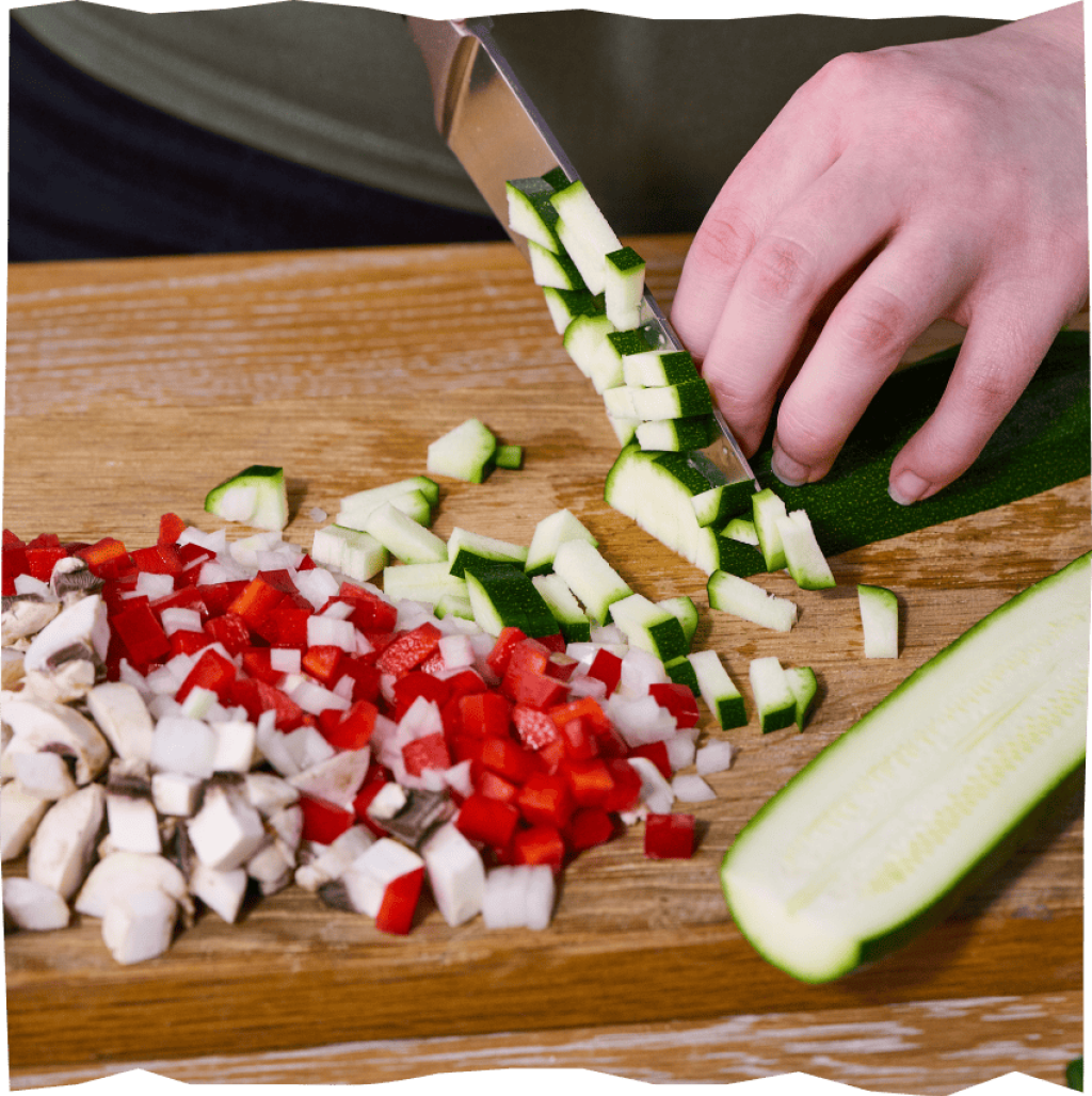 Gemüse (Zucchini, Paprika, Champignons) für gefüllte Kartoffelküchlein in Würfel schneiden.