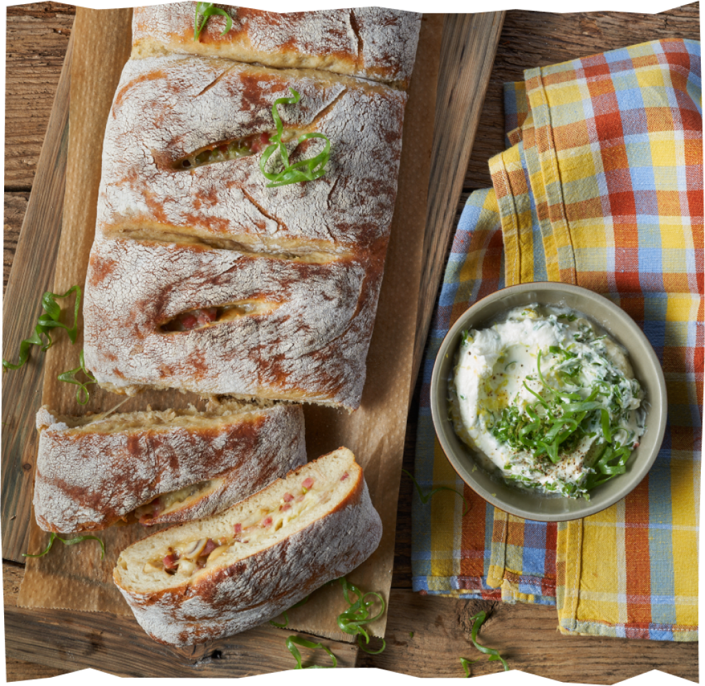 Frisch gebackenes Handbrot mit Champignon-Speck-Füllung und einem Schmand-Zitrone-Dip von oben fotografiert.
