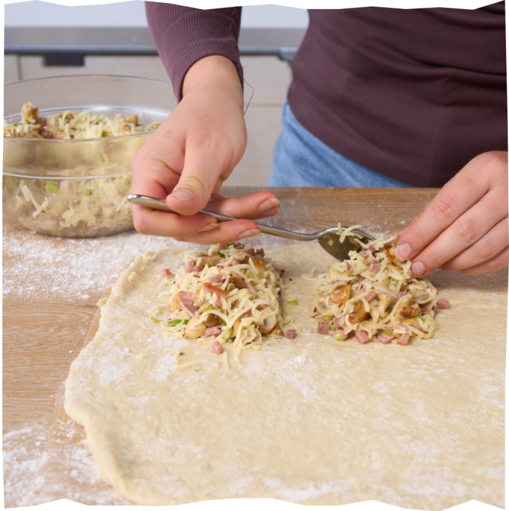 Ausgerollten Brotteig mit Schinken-Käse-Champignon-Füllung befüllen.
