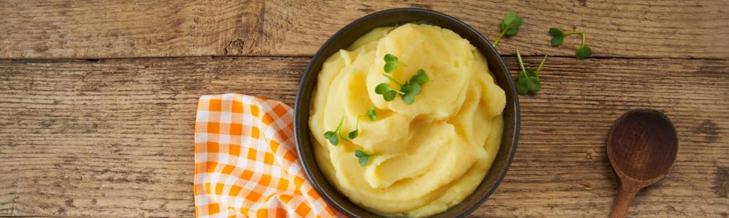Kartoffelpüree mit Kochlöffel und kariertem Geschirrtuch.