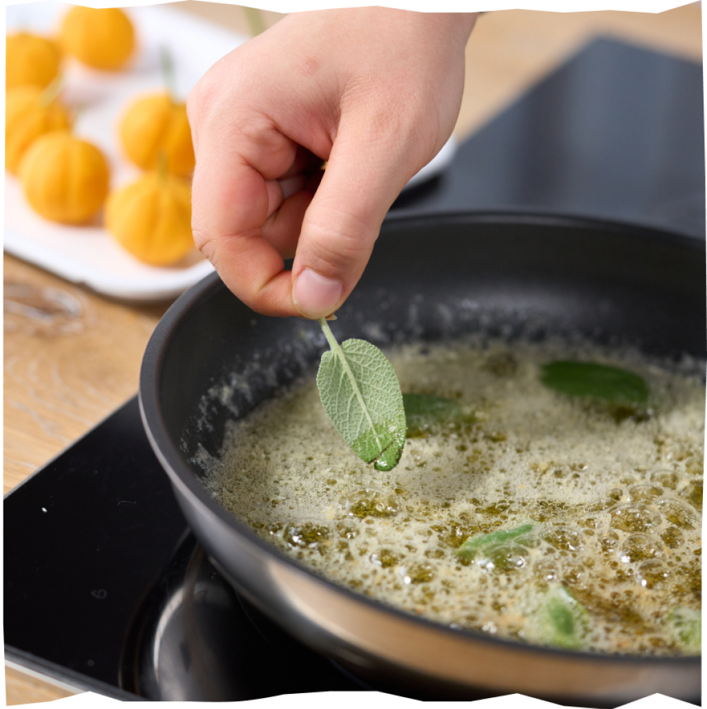 Zerlassene Butter in einer Pfanne mit Salbeiblättern und Kürbis-Gnocchi im Hintergrund.