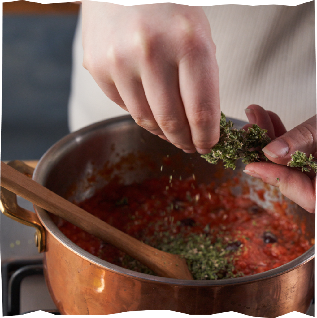 Basilikum fein schneiden und mit dem Oregano zur Sauce geben.