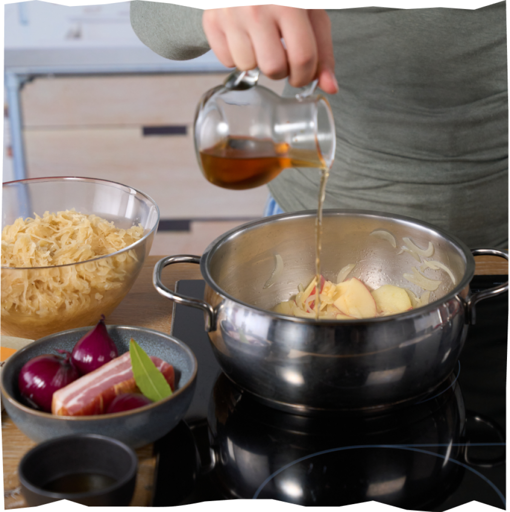 Ablöschen des Apfel-Zwiebel-Gemischs mit Apfelsaft, sodass im nächsten Schritt Sauerkraut & Lorbeerblätter hinzugefügt werden können.