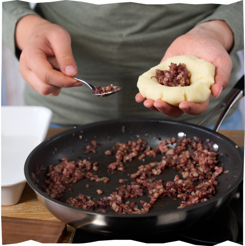 Befüllung der Kloßteigschiffchen mit der Speck-Zwiebel-Füllung und formen von Kartoffelkloß-Bällchen.