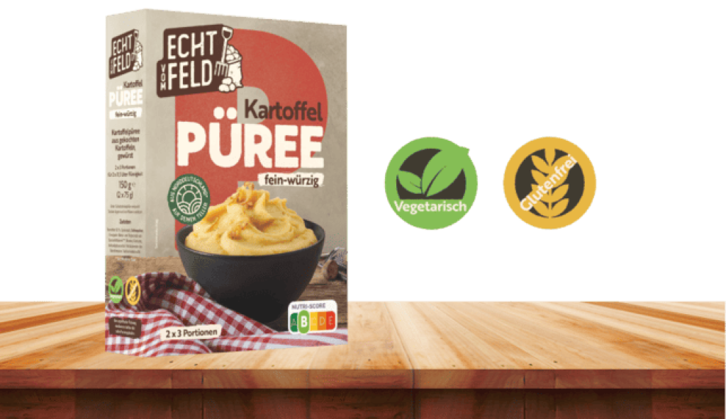 Eine Packung Echt vom Feld Kartoffelpüree auf einem Holzbrett. Daneben zwei Symbole für vegetarisch und glutenfrei.