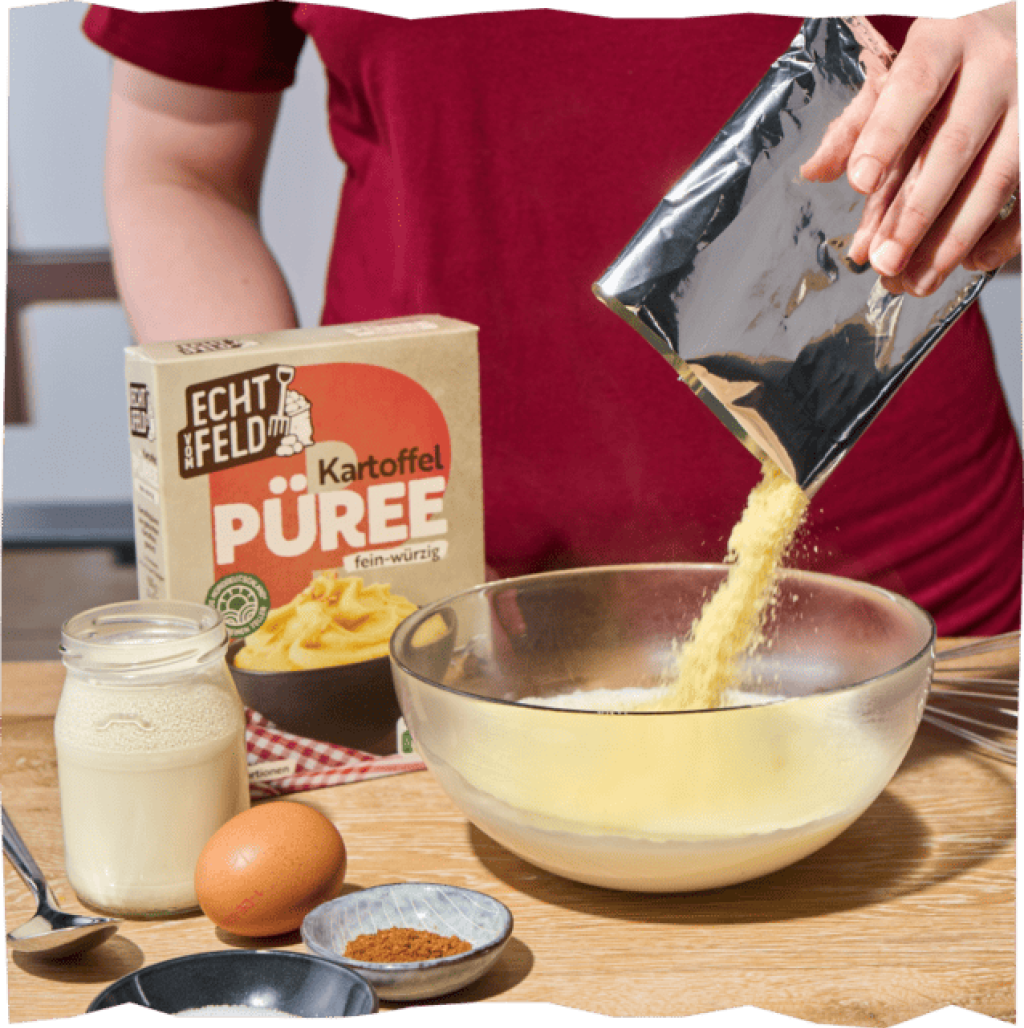 Das Kartoffelpüree-Pulver wird mit einem Schneebesen in eine Glasschale gerührt. Daneben ein Ei, Butter, Gewürze.