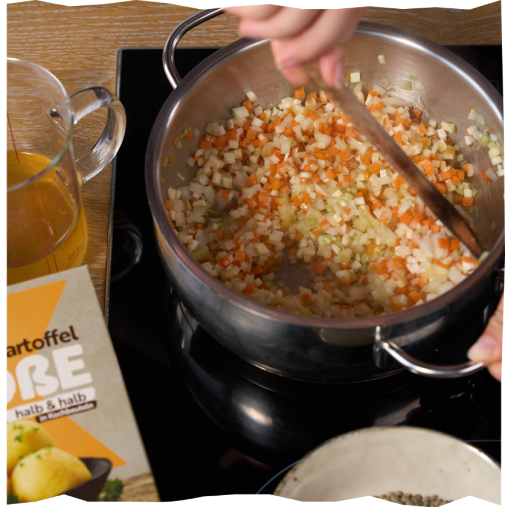 Zutaten für eine Linsen-Bolognese, die in einem Kochtop angeschwitzt werden.