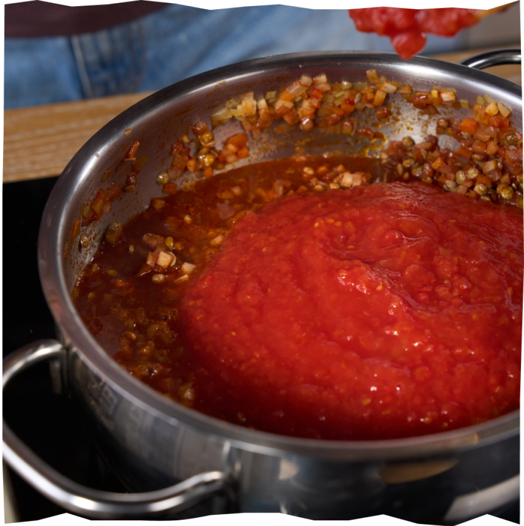 Ergänzen des Bolognese-Gemüses um Fond, gehackte Tomaten und Gewürze.