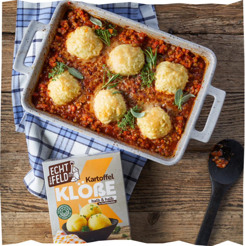 Mit Parmesan überbackene Linsen-Bolognese mit Echt vom Feld Kartoffelklößen in einer Auflaufform.