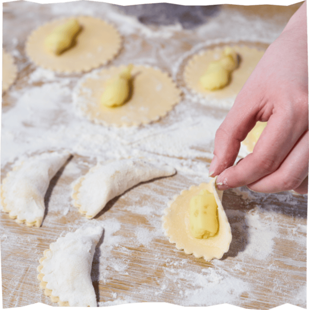 Teigränder für Kartoffel-Pilz-Piroggi befeuchten und zuklappen.