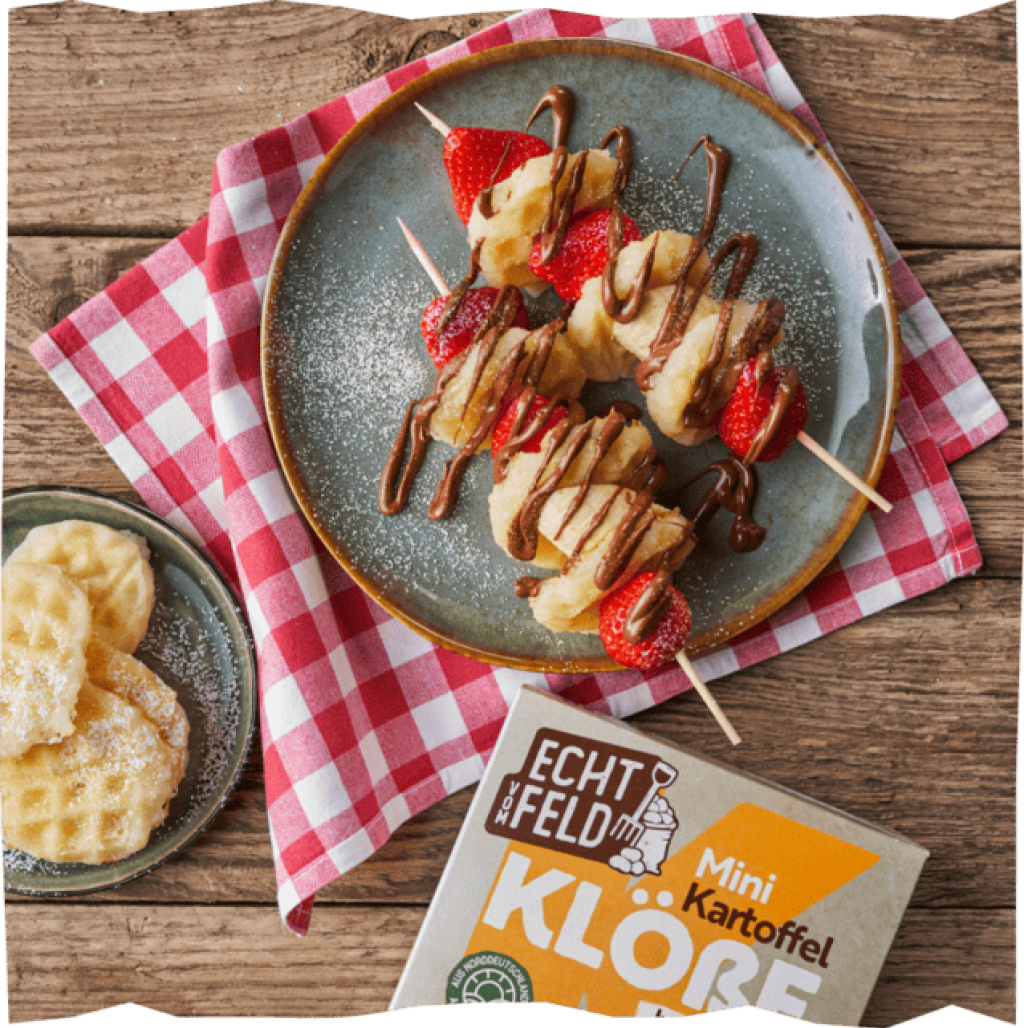 Fruchtig-Süße Kartoffelkloß-Spieße mit Schokoladensoße auf einer rot karierten Stoffserviette.