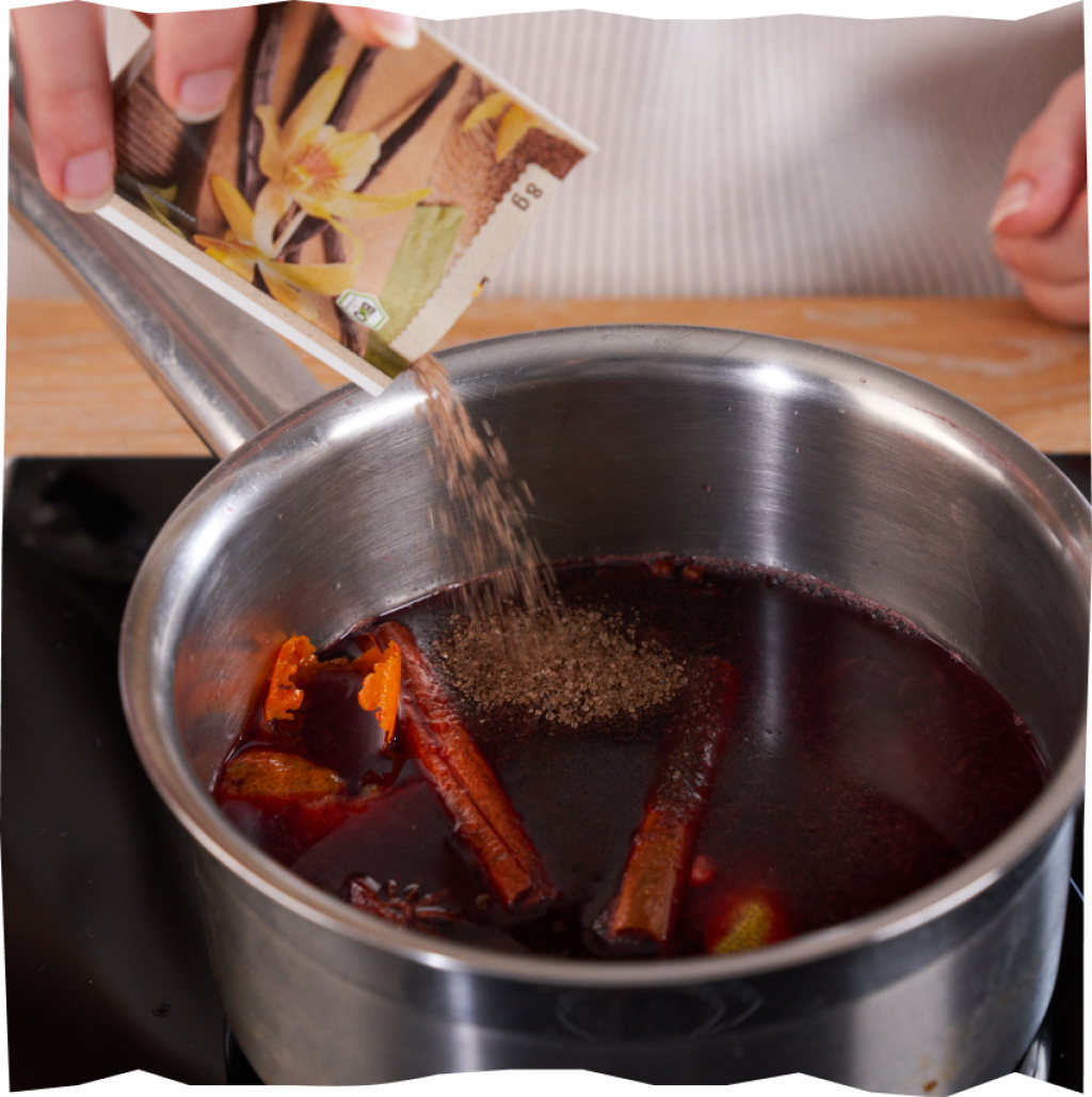 Glühwein-Kompott in einem Kochtopf mit Kirschen, Vanillezucker, Sternanis, Zimt und Nelken.