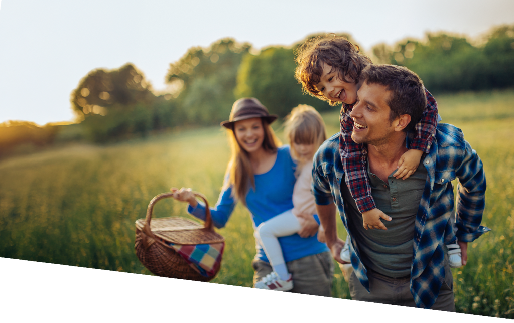 Glückliche Familie auf einem Feld mit einem Picknickkorb.