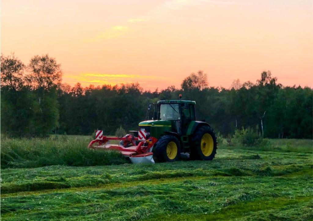 Traktor auf einem Feld beim Sonnenaufgang.